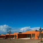 Atelier dos Remédios, Madalena Cardoso de Menezes, and Francisco Teixeira Bastos’ design of the 18 Red Row Houses at Bom Sucesso Resort featuring vibrant orange façades with modern angular rooflines and large windows.