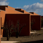 Atelier dos Remédios, Madalena Cardoso de Menezes, and Francisco Teixeira Bastos’ 18 Red Row Houses at Bom Sucesso Resort featuring orange composite material façades with daylighting effects and dynamic shadow patterns.
