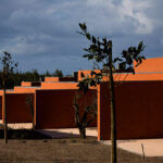 Atelier dos Remédios, Madalena Cardoso de Menezes, and Francisco Teixeira Bastos’ 18 Red Row Houses at Bom Sucesso Resort featuring vibrant orange composite material façades with sharp shadows highlighting the modern linear design.