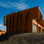 Atelier dos Remédios, Madalena Cardoso de Menezes, and Francisco Teixeira Bastos’ design of the 18 Red Row Houses at Bom Sucesso Resort featuring orange composite material façades with daylighting effects and distinct shadow patterns.