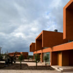 Atelier dos Remédios, Madalena Cardoso de Menezes, and Francisco Teixeira Bastos’ 18 Red Row Houses at Bom Sucesso Resort featuring a series of orange composite material façades with modern, linear assemblies.