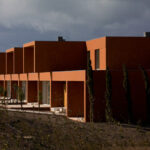 Atelier dos Remédios, Madalena Cardoso de Menezes, and Francisco Teixeira Bastos’ design of the 18 Red Row Houses at Bom Sucesso Resort featuring vibrant orange façades and modern angular rooflines.