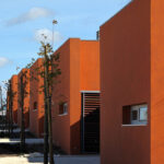 Atelier dos Remédios, Madalena Cardoso de Menezes, and Francisco Teixeira Bastos’ 18 Red Row Houses at Bom Sucesso Resort featuring a series of orange composite material façades with modern, linear assemblies.