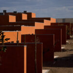 Atelier dos Remédios, Madalena Cardoso de Menezes, and Francisco Teixeira Bastos’ 18 Red Row Houses at Bom Sucesso Resort featuring orange composite material façades with sharp shadows highlighting the building’s linear assemblies.