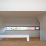 Atelier dos Remédios, Madalena Cardoso de Menezes, and Francisco Teixeira Bastos’ design of the 18 Red Row Houses at Bom Sucesso Resort showcasing interior wood flooring, hardwood stairs, composite material ceiling, and modern architectural elements.