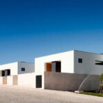 Atelier dos Remédios, Madalena Cardoso de Menezes, and Francisco Teixeira Bastos’ 18 Row Houses at Bom Sucesso Resort showcasing modern architecture with composite material and concrete façades arranged in a linear row formation.