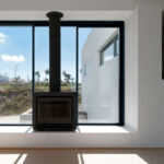 Atelier dos Remédios, Madalena Cardoso de Menezes, and Francisco Teixeira Bastos’ 18 Row Houses at Bom Sucesso Resort featuring modern wood flooring, expansive glass windows for daylighting, and a sleek grey interior design.
