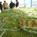 Gonçalo Cardoso de Menezes' Former Sales Office at Bom Sucesso Resort shown in a bird's-eye view scale model highlighting the building's modern glass façade, cantilevered structure, and surrounding landscaped park.