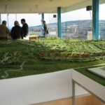 Gonçalo Cardoso de Menezes’ Former Sales Office at Bom Sucesso Resort shown in an aerial bird's-eye view featuring a scale model with modern angular forms and a glass façade.