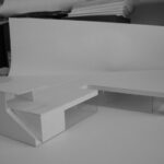 Josep Llinás’s House Model 2 showcasing a modern interior with hardwood wood flooring, plywood furniture, a composite material desk, and minimalist design elements.
