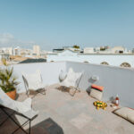 Manuel Gomes da Costa’s Modernist Faro showcasing a sleek apartment balcony with outdoor furniture, houseplants, and floor-to-ceiling glass panels.