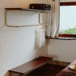 Manuel Gomes da Costa’s The Modernist Faro interior showcasing wood-stained shelving with hardwood varnish, plywood elements, modern light fixtures, lamps, and curtains.