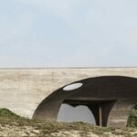 Manuel Aires Mateus’s Casa Na Terra showcasing a minimalist concrete bridge structure with composite materials and extensive daylighting features.