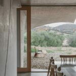 Manuel Aires Mateus’s Casa Na Terra showcasing a minimalist design with exposed concrete walls, wooden beams, and composite material planks creating a natural, earthy aesthetic.
