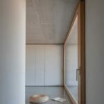 Manuel Aires Mateus’s Casa Na Terra showcasing a minimalist design with natural wood flooring, exposed concrete walls, and a wooden ceiling emphasizing organic materials and clean lines.