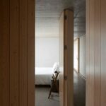 Manuel Aires Mateus’s Casa Na Terra showcasing an interior with hardwood wood flooring, wooden plank walls, and a composite material ceiling creating a warm, natural ambiance.