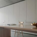 Manuel Aires Mateus’s Casa Na Terra interior showcasing wood flooring, hardwood furniture, grey wood stain finishes, and minimalist countertop design.