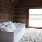 Manuel Aires Mateus’s Casas na Areia showcasing natural wood flooring with hardwood planks and composite materials in a minimalist bedroom setting.