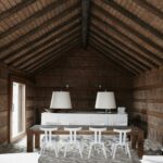 Manuel Aires Mateus’s Casas na Areia showcasing an interior with exposed wooden beams, hardwood plank flooring, minimalist wooden furniture, and a natural wood ceiling emphasizing warm textures and clean lines.