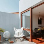 Manuel Gomes da Costa’s The Modernist Faro showcasing a composite material wall, wooden balcony with houseplants in flowerpots, and extensive daylighting through shaded areas.