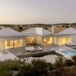 Nuno Brandao Costa’s Pura Comporta villa showcasing a modern estate with clean lines, white façades, and expansive glass windows blending indoor and outdoor living.