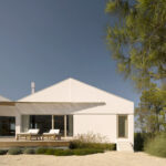 Nuno Brandao Costa’s Pura Comporta showcasing a modern farmhouse with a pitched roof, shaded outdoor areas, and rustic estate elements.