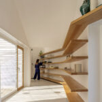 Nuno Brandao Costa’s Pura Comporta interior showcasing wood flooring, composite material shelving, stained wood ceiling, and minimalist stair design.