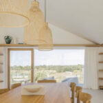 Nuno Brandao Costa’s Pura Comporta showcasing a natural wood ceiling with stained hardwood panels, plywood elements, modern light fixtures, and a minimalist chandelier.