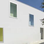 Ricardo Bak Gordon’s Casa em Sobral da Lagoa showcasing a minimalist design with composite material walls, smooth plaster finishes, concrete elements, and strategic daylighting enhancing the painted surfaces.