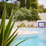 Casa Veiga / Casa Portufornia, Colares by Manuel Tainha, Rui Costa Martins (3737) Manuel Tainha and Rui Costa Martins’ Casa Veiga / Casa Portufornia showcasing a modern design with extensive glass façades, landscaped garden with shrubs and woody plants, a shaded yard, and an integrated swimming pool.