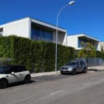 Eduardo Souto de Moura’s Utopia Villa 7 showcasing a sleek modern design with clean lines and large glass windows, complemented by a personal luxury sedan parked nearby.