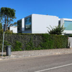 Francisco Aires Mateus’s Utopia Villa 1 showcasing a modern villa with clean lines, extensive balconies, integrated landscaping with hedges and shrubs, and thoughtful daylighting enhancing the urban estate design.