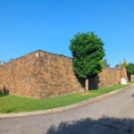 Quinta da Barca Villa 1, Esposende by João Alvaro Rocha (3720) João Alvaro Rocha’s Quinta da Barca Villa 1 showcasing a stone and brick wall exterior with detailed brickwork, a paved walkway, and a driveway leading to the modern residential building.