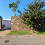 Quinta da Barca Villa 1, Esposende by João Alvaro Rocha (3722) João Alvaro Rocha’s Quinta da Barca Villa 1 showcasing a brick façade with shaded landscaping, palm trees, a tar driveway, and a walkway surrounded by woody plants.