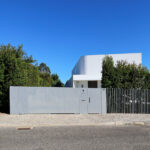 Unknown Architect’s Utopia Villa 14 showcasing a composite material and concrete structure with a shaded entrance, modern gate, and home fencing surrounding the property.