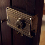 Casa Veiga / Casa Portufornia, Colares by Manuel Tainha, Rui Costa Martins (3739) Manuel Tainha and Rui Costa Martins’ Casa Veiga / Casa Portufornia showcasing a wooden door with metal household hardware, including a latch and handle, featuring rich brown wood stain and detailed lock elements.