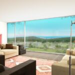 Eduardo Souto de Moura’s 10 Architectural "Hilltop" Villas, Lot 113, showcasing a modern living room interior with minimalist furniture, wooden flooring, a sleek couch, table, chairs, and a high ceiling.