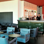 Nuno Graça Moura’s Tennis Club, Lot 161 interior showcasing modern furniture with sleek chairs and tables, wooden flooring, a spacious room layout, and a ceiling designed for comfort and style.