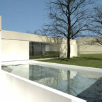 Inês Lobo’s 6 Architectural Villas, Lot 349, showcasing a courtyard with plaster walls, concrete and composite material elements, tiled surfaces, and strategic daylighting creating dynamic shadows and shaded areas.