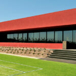 Nuno Graça Moura’s Tennis Club, Lot 161, showcasing a modern design with artificial turf lawn, shaded park areas, and vibrant red accents.