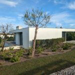 Alcino Soutinho’s 10 Architectural Villas, Lot 240, showcasing a modern concrete villa with extensive landscaping, shaded garden areas, and large windows optimizing daylighting.
