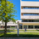 Alcino Soutinho’s Biblioteca Municipal Florbela Espanca showcasing a brutalist architecture style with composite material façade, urban design elements, and shaded areas in a daytime campus setting.