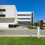 Alcino Soutinho’s Biblioteca Municipal Florbela Espanca showcasing a brutalist architecture style with composite material façade, landscaped courtyard with lawn and shade elements, and urban design features typical of a corporate headquarters campus.