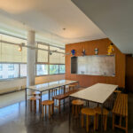 Alcino Soutinho’s Biblioteca Municipal Florbela Espanca interior showcasing hardwood flooring, varnished wood furniture, expansive glass windows allowing natural daylighting, and a detailed ceiling design.