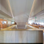 Alcino Soutinho’s Biblioteca Municipal Florbela Espanca interior showcasing wood flooring and ceiling, composite materials, metal structural elements, extensive glass panels, and optimized daylighting for a modern, engineered design.