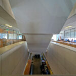 Alcino Soutinho’s Biblioteca Municipal Florbela Espanca interior showcasing composite material flooring, metal and glass elements, modern lighting fixtures, and a sleek ceiling design.