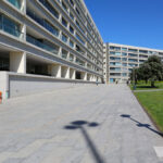 Alcino Soutinho’s Conjunto Habitacional Palácio da Enseada showcasing a high-rise condominium with composite material façade, glass balconies, and urban design elements in a metropolitan area during daytime.