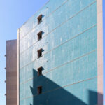Alcino Soutinho’s Conjunto Habitacional Palácio da Enseada showcasing a high-rise condominium with a blue glass façade, composite materials, and modern engineering elements under daytime lighting.