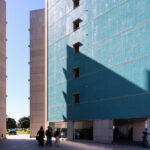 Alcino Soutinho’s Conjunto Habitacional Palácio da Enseada showcasing a high-rise condominium with a composite and concrete structure, featuring expansive glass façades under a clear blue daytime sky.