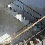 Alcino Soutinho’s Conjunto Residencial Varandas de Venezuela showcasing a daytime view of the building’s grey composite material façade with metal handrails, iron stairs, and extensive glass elements enhancing daylighting.